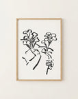 The image is a framed artwork depicting a stylized floral design in black and white.